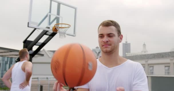 法廷でバスケットボールをしている白人バスケットボール選手の正面図 彼は指4Kでバスケットボールを回転させている — ストック動画