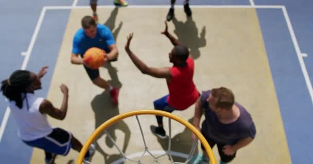 バスケットボールコートでバスケットボールをしている多民族バスケットボール選手の高角図 4Kでゴールを決める — ストック動画