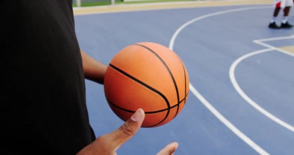 バスケットボールコートでバスケットボールで遊ぶバスケットボール選手のミッドセクション 彼は手でバスケットボールのバランスをとっている — ストック動画