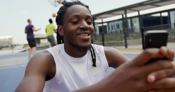 Vista Frontal Del Jugador Baloncesto Afroamericano Usando Teléfono Móvil Cancha — Vídeo de stock