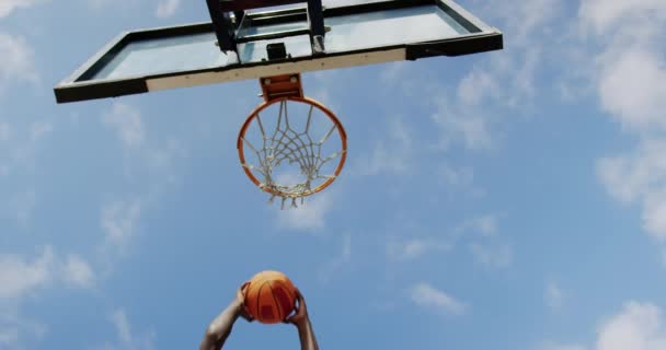 バスケットボールコートでバスケットボールをしているアフリカ系アメリカ人バスケットボール選手の低角度の眺め 彼はゴール4Kを作っている — ストック動画