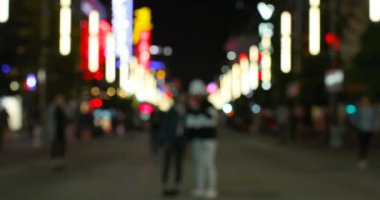 Geceleri renkli bulanık şehrin ön görünümü. Yayalar 4k sokakta yürüyor