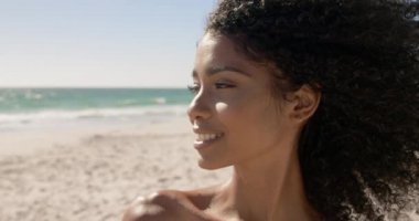 Sahilde duran Afro-Amerikan kadının ön görünümü. O gülümsüyor ve kamera 4k bakıyor