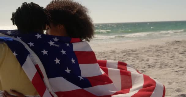 Vista Trasera Pareja Afroamericana Envuelta Bandera Americana Sentados Juntos Playa — Vídeo de stock