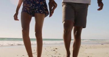 Afrikalı Amerikalı çiftin orta bölümünde sahilde birlikte yürüyorlar. El ele tutuşuyorlar 4k