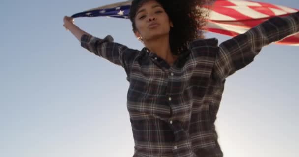 햇빛에 해변에서 국기를 흔들고 아프리카 미국인 여성의 각도보기 카메라 — 비디오