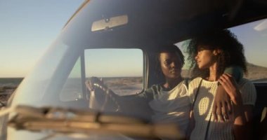 Afrikalı Amerikalı çift in ön görünümü bir plaj da kamyonet birlikte oturuyor. Birbirlerine 4k bakıyorlar.