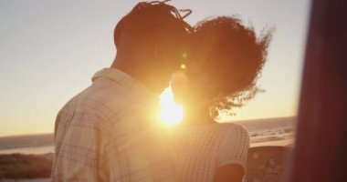 Afro-Amerikalı çift plajda kamyonet yakınında birbirlerine kucaklıyor. Onlar kafa kafaya 4k vardır