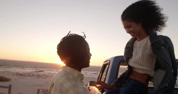 日没時にビーチで抱き合うアフリカ系アメリカ人カップルのサイドビュー 笑顔で4K — ストック動画