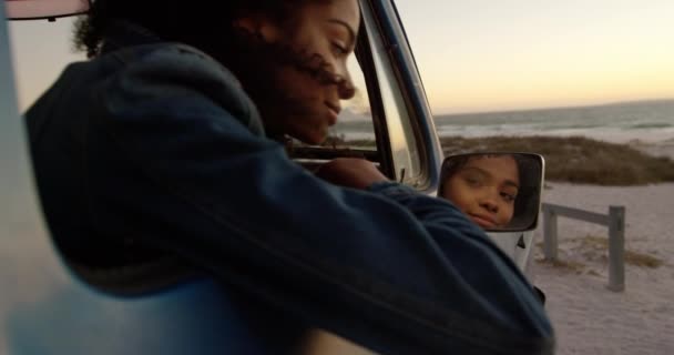 在海滩看着小卡车的翼镜的非洲裔美国妇女侧视图 她微笑着4K — 图库视频影像