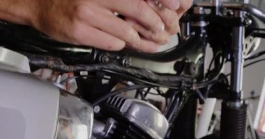 Motosiklet tamir garajında cep telefonu kullanan Kafkas erkek tamircisinin yakın çekim. O gülümsüyor ve metin 4k mesaj