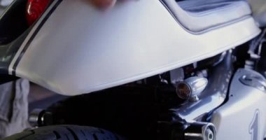 Onarım garajında motosiklet temizliği beyaz erkek mekanik yakın çekim. Kırmızı fren lambası yanıp sönen 4k