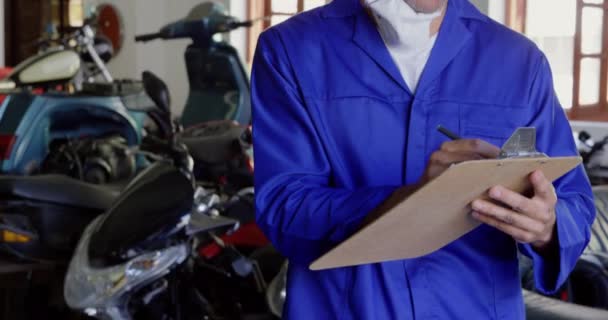 Vista Frontal Escritura Mecánica Masculina Caucásica Portapapeles Garaje Reparación Motocicletas — Vídeos de Stock