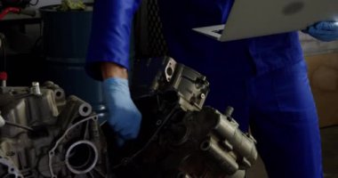 Garajda motosiklet motoru tamir ederken dizüstü bilgisayar kullanarak Kafkas erkek mekanik ön görünümü. Koruyucu maske takıyor.