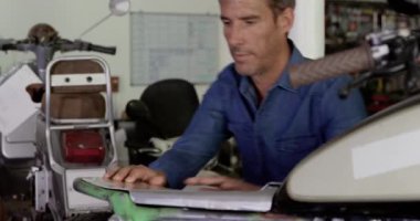 Onarım garajında motosiklet tamir Kafkas erkek mekanik ön görünümü. O motosiklet 4k yeni koltuk sabitleme