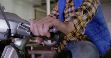 Beyaz erkek tamirci tamir garajında scooter tamir orta bölümü. Scooter freni ve gaz pedalı 4k'ı inceliyor.