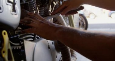 Tamir garajında motosiklet tamir eden Kafkas erkek tamircisinin yakın çekimi. O spanner aracı 4k kullanıyor