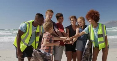 Sahilde el yığınları oluşturan çeşitli gönüllülerin ön görüntüsü. Gülümsüyorlar. 