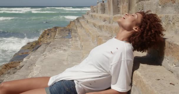 Vista Lateral Mujer Afroamericana Relajándose Playa Día Soleado Ella Sonríe — Vídeo de stock