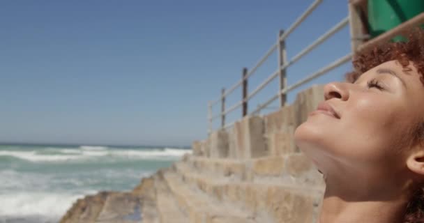 Vista Lateral Mujer Afroamericana Relajándose Playa Día Soleado Ella Sonríe — Vídeo de stock