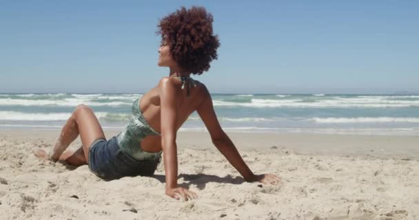ビーチでくつろぐ若いアフリカ系アメリカ人女性のサイドビュー 彼女は太陽の下で日焼けしている — ストック動画