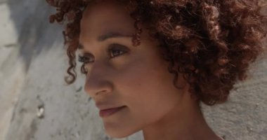 Güneş ışığı altında sahilde dinlenen genç Afrikalı-Amerikalı kadının yakın çekim. O kamera 4k bakıyor
