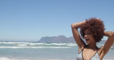 Sahilde dijital kamera ile Afrikalı Amerikalı kadının fotoğraflarını çeken genç Afrikalı Amerikalı adam ön görünümü. O gülümsüyor ve 4k poz