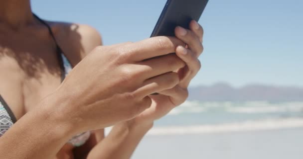 Vista Frontal Una Joven Afroamericana Bikini Con Teléfono Móvil Playa — Vídeo de stock