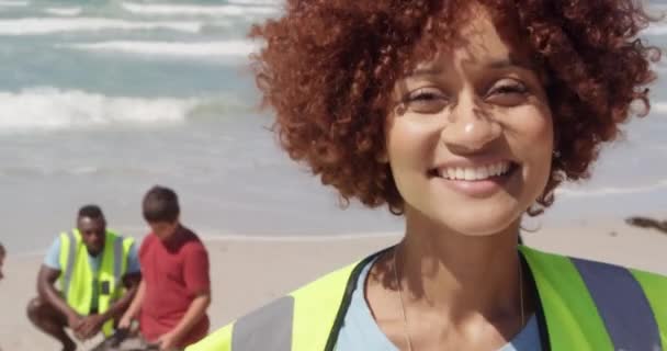 非洲裔美国女性志愿者在海滩上看着镜头的镜头 她带着微笑面对着各种各样的志愿者 — 图库视频影像