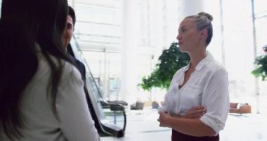 Muhtelif iş adamları ofisin lobisinde birbirleriyle iletişim halindeler. El sıkışıyorlar.