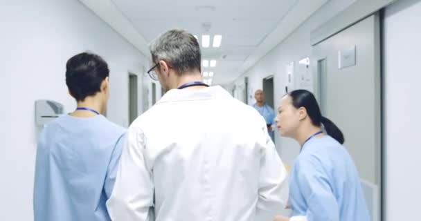 Waist Volg Shot Van Drie Artsen Lopen Door Ziekenhuisgang Praten — Stockvideo