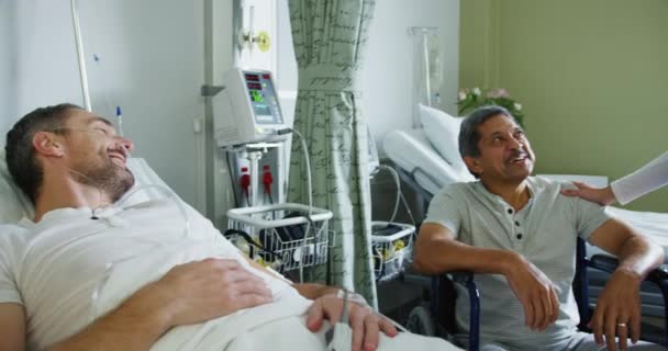 Tekerlekli Sandalyedeki Orta Yaşlı Bir Adamın Hastane Koğuşunda Yatan Genç — Stok video