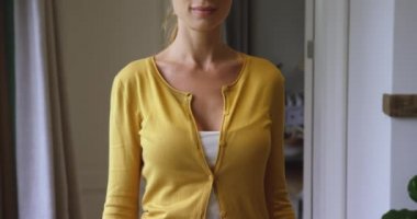 Rahat bir evde kameraya bakan Beyaz kadın ön görünümü. O 4k gülümsüyor