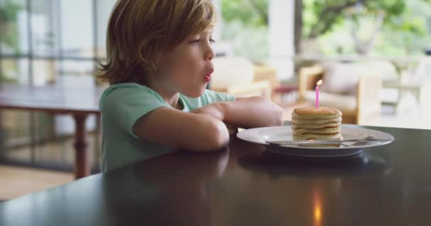 Zijaanzicht Van Kaukasische Jongen Waait Kaars Pannenkoek Aan Eettafel Keuken — Stockvideo