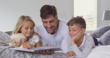 Kafkas baba ve çocukları evde yatak odasında hikaye kitabı okuma ön görünümü. Onlar gülümsüyor ve 4k etkileşim