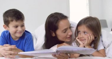 Kafkas anne ve çocukları evde yatak odasında hikaye kitabı okuma yakın çekim. Onlar gülümsüyor ve birbirleriyle etkileşim 4k