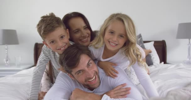 自宅で寝室で楽しんで白人の家族の正面図 彼らは微笑んでカメラ4Kを見ている — ストック動画