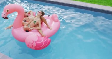 Beyaz çiftin yüzme havuzunda şişme tüpüzerinde birlikte yatarken ki yüksek açı görüntüsü. Onlar 4k uykuda