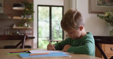 Beyaz çocuğun evdeki masada ödevini yapmasını yan görüyorum. Yoğunlaştı ve 4K 'ya odaklandı.