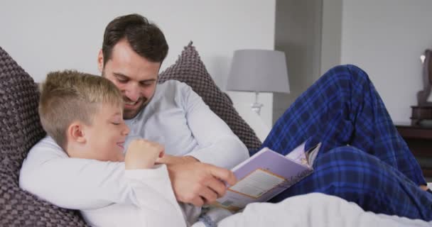 Vista Lateral Del Padre Hijo Caucásicos Leyendo Libro Cuentos Cama — Vídeo de stock