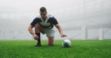 Stadyumda ayakkabı bağlayan beyaz erkek rugby oyuncusunun ön görüntüsü. 4 bin rugby topuyla koşuyor.  