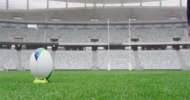 Stadyumda rugby oynayan erkek ragbi oyuncusunun alt tarafı rugby topu 4K 'yı tekmeliyor.