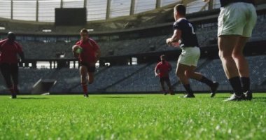 Stadyumda rugby oynayan çeşitli rugby oyuncularının ön görüntüsü. Birbirlerine 4k koşuyorlar.