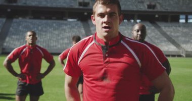 Kafkas erkek rugby oyuncusunun yakın çekimi stadyumda elleri kalçasında duruyor. Yorgun ve kamera 4K 'ye bakıyor.