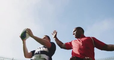 Stadyumda rugby oynayan farklı rugby oyuncularının düşük açılı görüntüsü. 4 bin rugby topu yakalıyorlar.