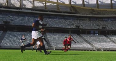 Stadyumda rugby oynayan çeşitli rugby oyuncularının yan görüntüsü. Birbirlerine dört bin dolar atıyorlar.