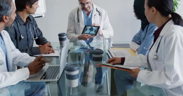 中年白种人男医生与一组医生在平板电脑上给他们看X光照片时的斜照 — 图库视频影像