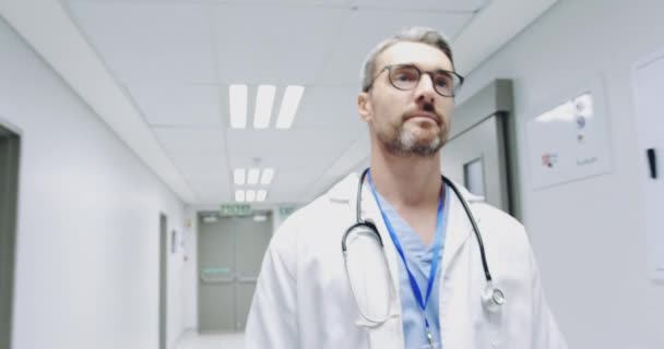 中年白种人男医生在医院走廊行走的低角度腰部反向跟踪拍摄 — 图库视频影像