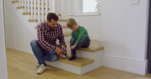 白种人父亲的侧视图 在舒适的家里系着儿子的鞋带 他们坐在楼梯4K — 图库视频影像