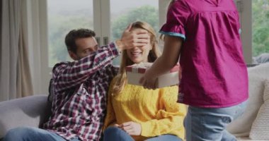 Rahat bir evde kanepeüzerinde annesine bir hediye veren Kafkas kızı ön görünümü. Baba el 4k ile anne gözleri kapanış